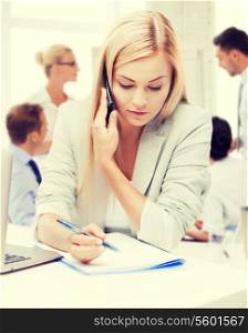 business concept - businesswoman talking on the phone and taking notes in office