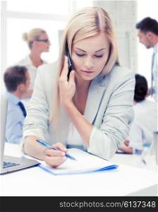 business concept - businesswoman talking on the phone and taking notes in office. businesswoman with phone in office