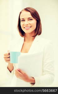 business concept - businesswoman with cup of coffee and folders in office