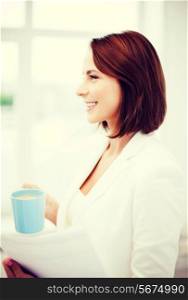 business concept - businesswoman with cup of coffee and papers in office