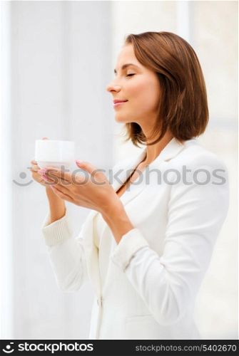 business concept - businesswoman with cup of coffee in office
