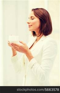 business concept - businesswoman with cup of coffee in office