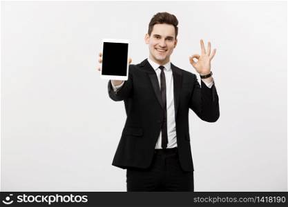Business Concept: Cheerful businessman in smart suit with pc tablet showing ok. Isolated over grey background. Business Concept: Cheerful businessman in smart suit with pc tablet showing ok. Isolated over grey background.