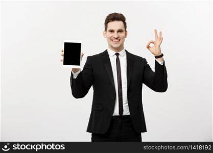 Business Concept: Cheerful businessman in smart suit with pc tablet showing ok. Isolated over grey background. Business Concept: Cheerful businessman in smart suit with pc tablet showing ok. Isolated over grey background.