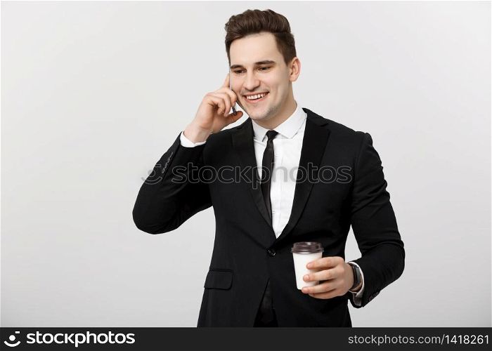 Business Concept: Close-up confident young handsome businessman talking on cell phone and drinking coffee over white isolated background. Business Concept: Close-up confident young handsome businessman talking on cell phone and drinking coffee over white isolated background.