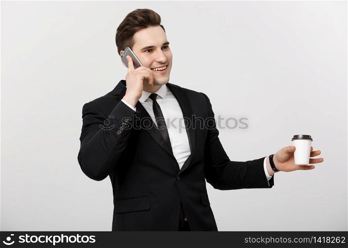 Business Concept: Close-up confident young handsome businessman talking on cell phone and drinking coffee over white isolated background. Business Concept: Close-up confident young handsome businessman talking on cell phone and drinking coffee over white isolated background.