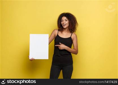 Business Concept - Close up Portrait young beautiful attractive African American smiling showing plain white blank sign. Yellow Pastel studio Background. Copy space.. Business Concept - Close up Portrait young beautiful attractive African American smiling showing plain white blank sign. Yellow Pastel studio Background. Copy space