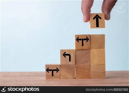 Business concept growth success process, Close up Businessman hand arranging wood cube with arrow stacking as step stair.