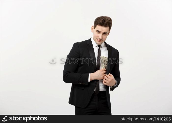 Business Concept: Handsome businessman in black suit taking dollars banknotes with stealthy expression against white background. Business Concept: Handsome businessman in black suit taking dollars banknotes with stealthy expression against white background.
