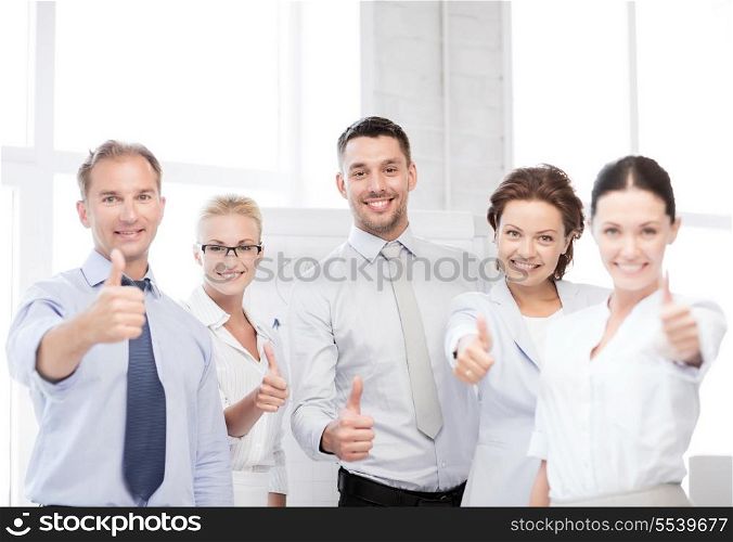 business concept - picture of happy business team showing thumbs up in office