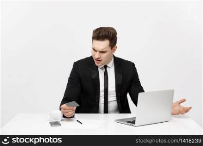 Business Concept: Portrait of young businessman using laptop computer and mobile phone holding debit card. Isolated over grey background. Business Concept: Portrait of young businessman using laptop computer and mobile phone holding debit card. Isolated over grey background.