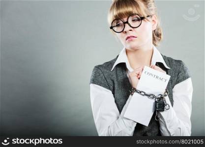 Business concept. Serious businesswoman with chained hands holding contract