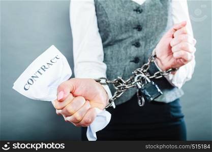 Business concept. Serious woman businesswoman with chained hands holding contract, side view grungy background