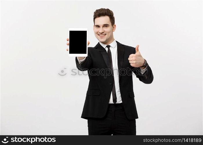 Business Concept: smiling businessman with tablet showing thumbs up over gray studio background.. Business Concept: smiling businessman with tablet showing thumbs up over gray studio background