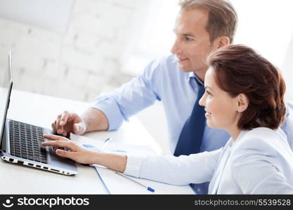 business concept - smiling businesswoman and businessman working with laptop in office