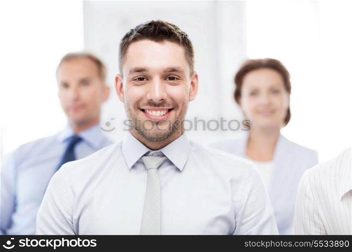 business concept - smiling handsome businessman with team in office