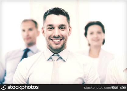 business concept - smiling handsome businessman with team in office