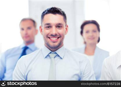 business concept - smiling handsome businessman with team in office. businessman in office