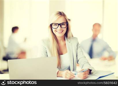 business concept - smiling woman with laptop, documents and pen in office