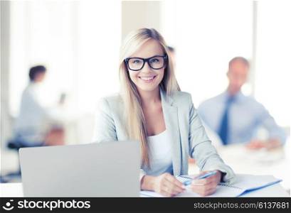 business concept - smiling woman with laptop, documents and pen in office