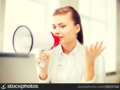 business concept - strict businesswoman shouting in megaphone in office