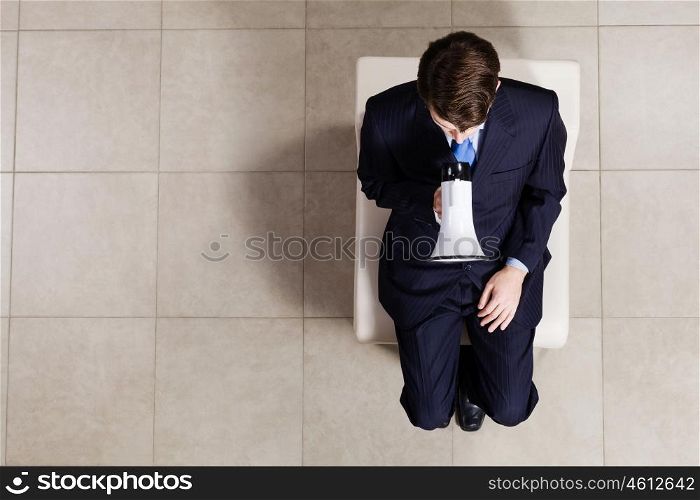 Business concept. Top view of businessman sitting on chair with megaphone