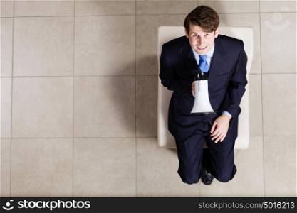 Business concept. Top view of businessman sitting on chair with megaphone