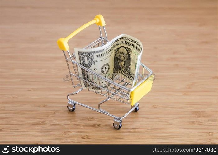 Business concept with American dollar and shopping cart on the wooden table