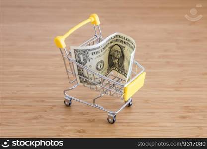 Business concept with American dollar and shopping cart on the wooden table