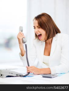 business concept - woman shouting into phone in office