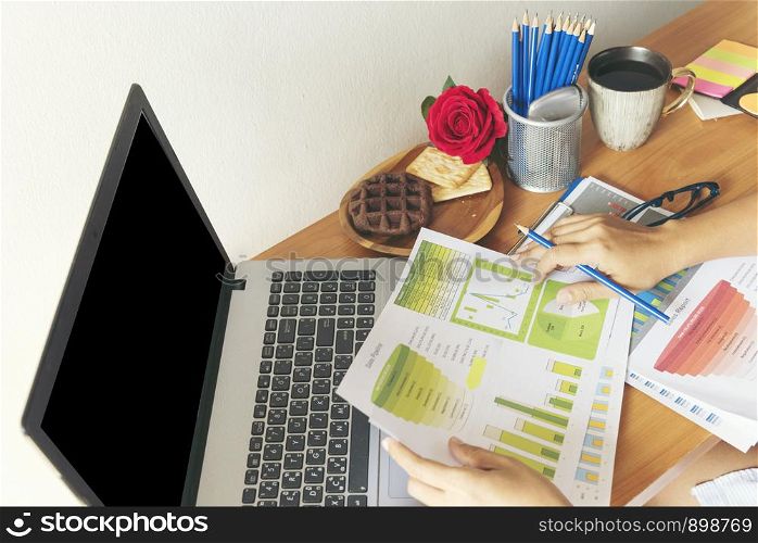 business concept. young beautiful woman using laptop and reading document report at her table.