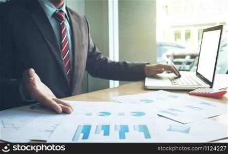 Business concept, Young business man&rsquo;s hands working with laptop and document graph on wood table.