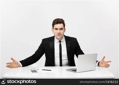 Business Concept: Young businessman working in bright office, sitting at desk, using laptop with serious facial expression.. Business Concept: Young businessman working in bright office, sitting at desk, using laptop with serious facial expression
