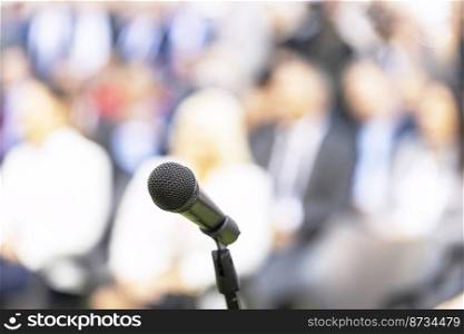 Business conference event, corporate presentation or training, microphone in the focus, blurred audience in the background