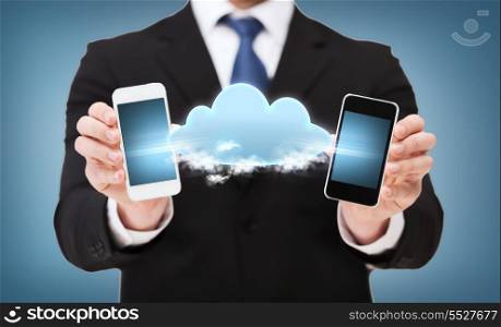 business, connectivity,internet and technology concept - businessman showing two smartphones black connected with cloud