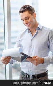 business, construction and office concept - smiling businessman with clipboard in office