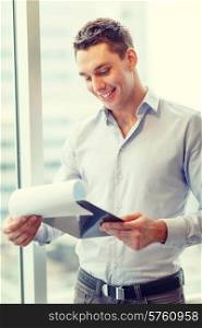business, construction and office concept - smiling businessman with clipboard in office