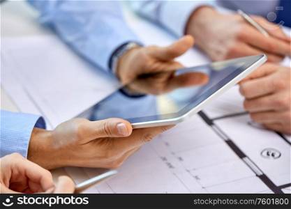 business, construction and people concept - group of architects with tablet pc computer and blueprint at office. architects with tablet pc and blueprint at office