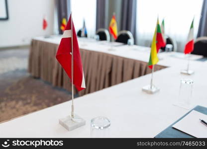 business, corporate and interior concept - flags on table in boardroom at international conference. flags at international conference boardroom