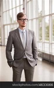 business, corporate and people concept - young businessman in suit and glasses at office