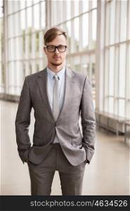 business, corporate and people concept - young businessman in suit and glasses at office