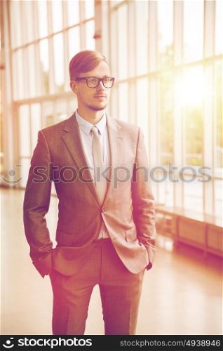 business, corporate and people concept - young businessman in suit and glasses at office. young businessman in suit and glasses at office