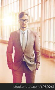 business, corporate and people concept - young businessman in suit and glasses at office. young businessman in suit and glasses at office
