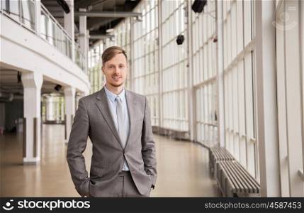 business, corporate and people concept - young businessman in suit at office building hall
