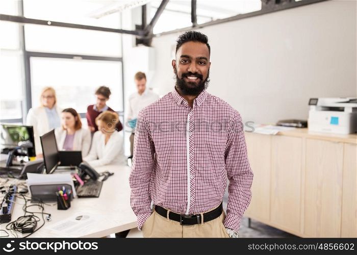 business, corporate, people and teamwork concept - happy indian man over creative team in office