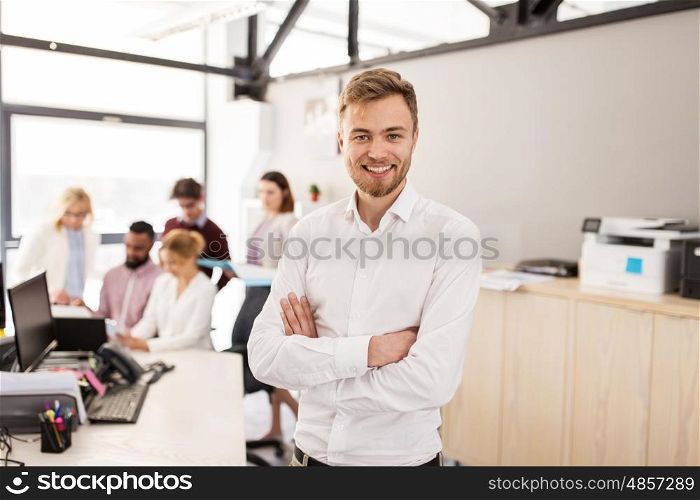 business, corporate, people and teamwork concept - happy young man over creative team in office