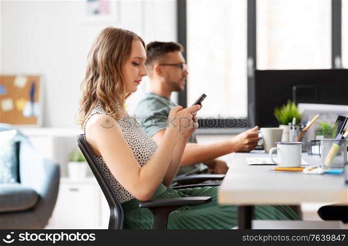 business, corporate, technology and people concept - businesswoman or female startupper using smartphone at office. businesswoman using smartphone at office