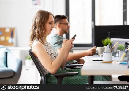 business, corporate, technology and people concept - businesswoman or female startupper using smartphone at office. businesswoman using smartphone at office