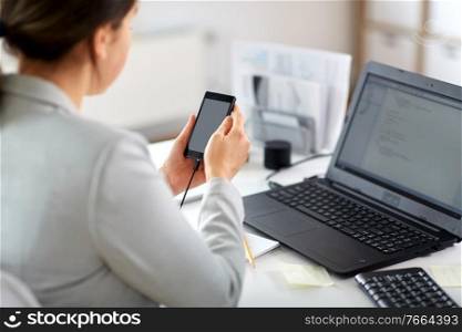 business, corporate, technology and people concept - businesswoman with smartphone working at office. businesswoman with smartphone working at office
