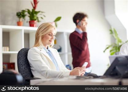 business corporate, technology and people concept - happy businesswoman texting on smartphones at office. happy businesswoman with smartphones at office